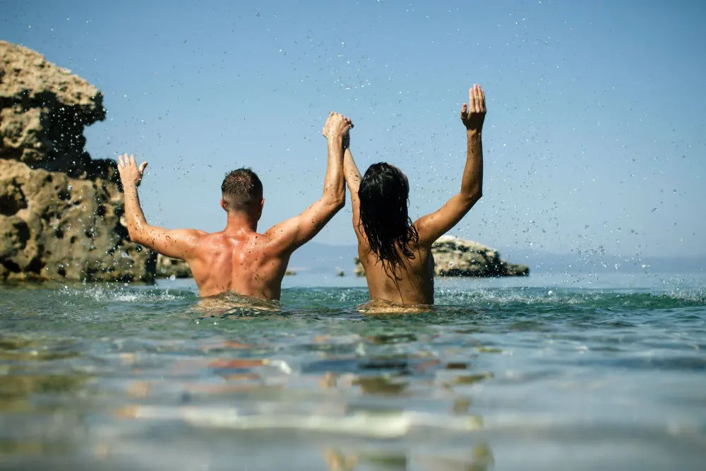 couple splashing water nude beach